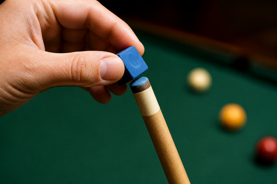 Hand lightly brushing blue chalk across a rounded leather pool-cue tip